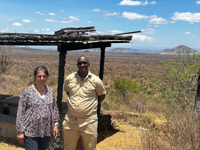       Two people posing in front of scenic mountains.
  