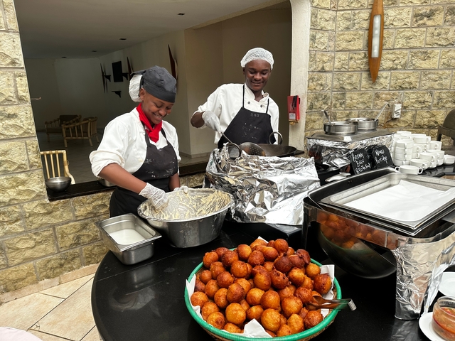 Chefs preparing food at an outdoor stall.