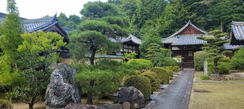 A traditional Japanese garden with a rock pathway and trimmed bushes.
