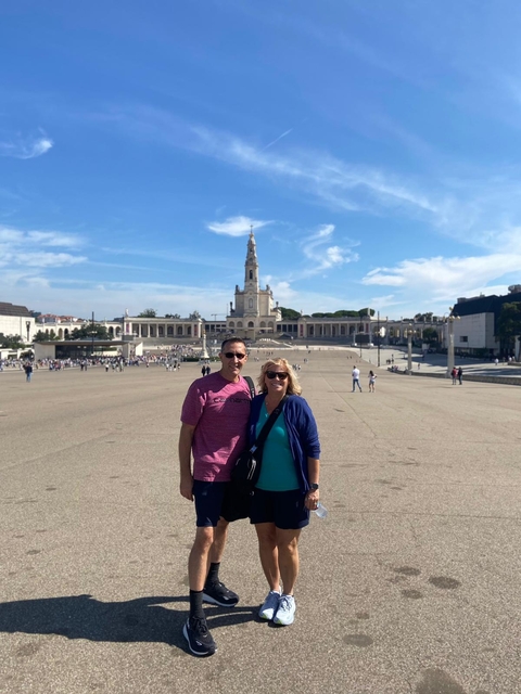 Couple posing in a large plaza with a historical building.