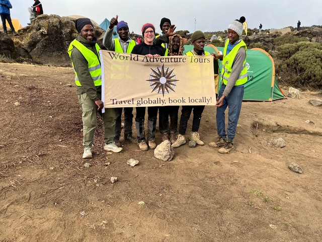 A group of people holding a banner at a campsite.