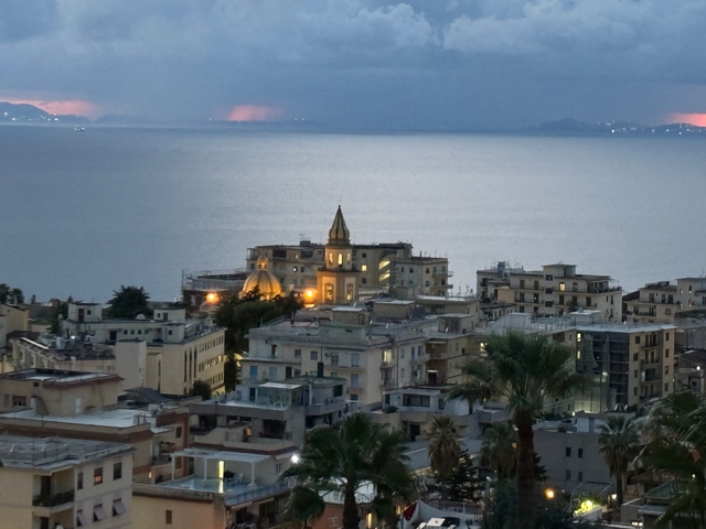       View of buildings by the sea during dusk.
  