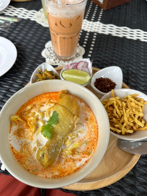 Bowl of spicy chicken curry with side condiments.