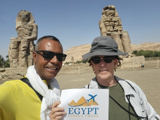 Two people posing in front of ancient statues, likely in Luxor.