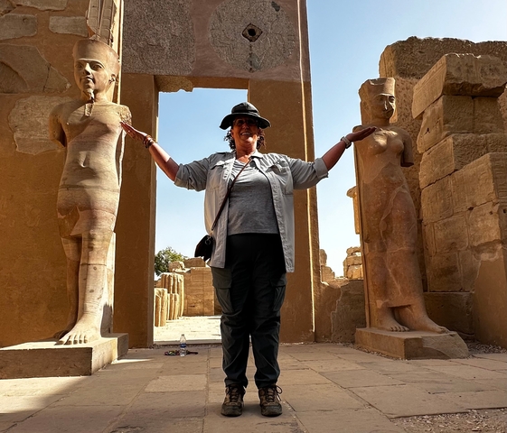 Tourist posing between ancient columns in a temple.