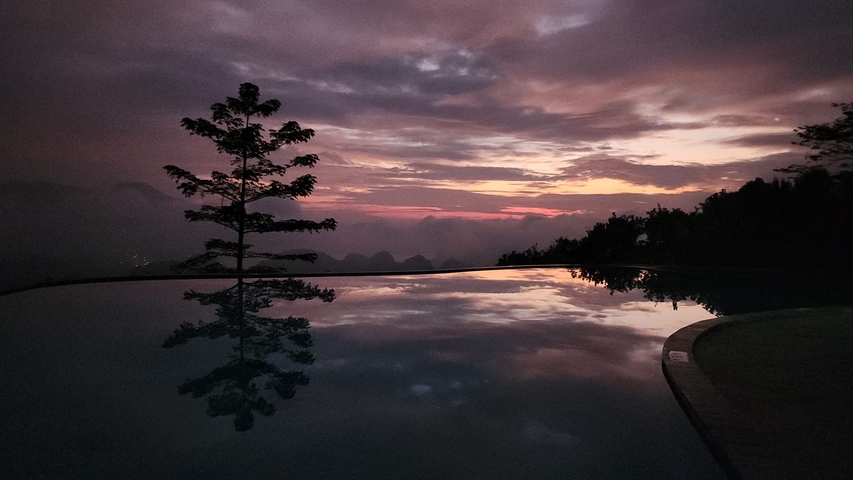 Beautiful sunset scene with a tree reflecting in a pool.