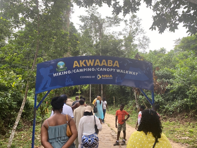       Group of people entering a hiking and camping area with a welcome sign.
  