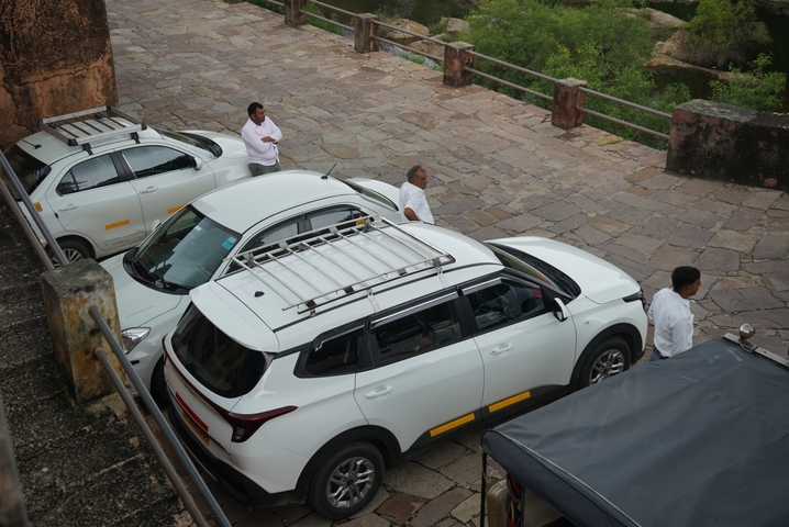       Group of people standing near parked white SUVs.
  