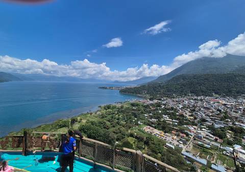 Panoramic view of a town by a large lake with people on a lookout.