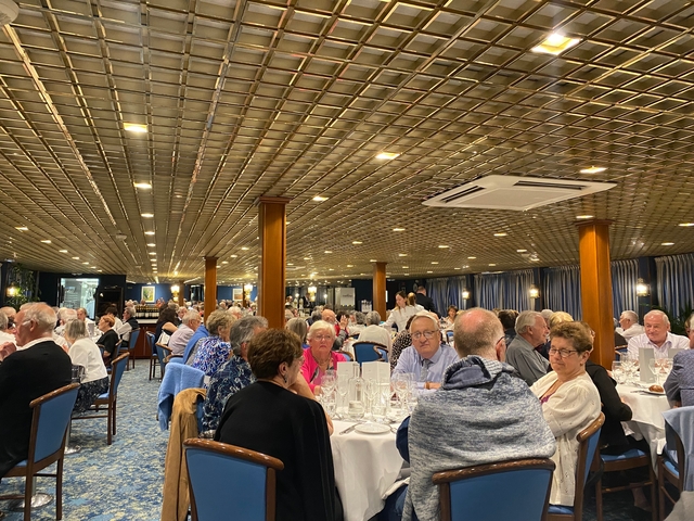 People dining together in a room with decorative ceiling.