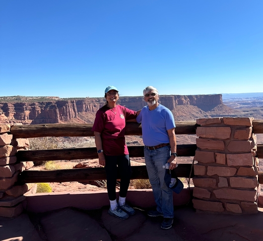 Two people posing in front of a canyon landscape.