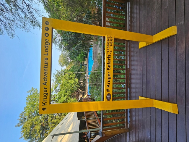 Signboard for Kruger Adventure Lodge with trees in the background.