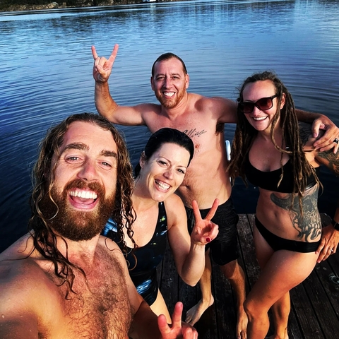       Group of friends swimming and posing by the water.
  