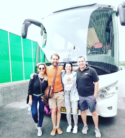       Friends posing in front of a tour bus.
  