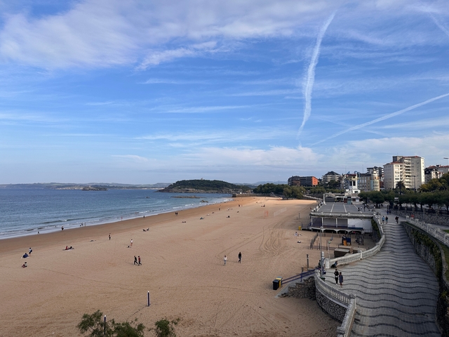       Sandy beach with a distant view of a city.
  