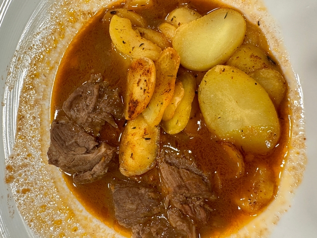       Plate of stew with meat and potatoes.
  