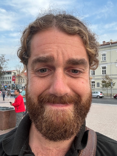Close-up of a person's face with a street in the background.