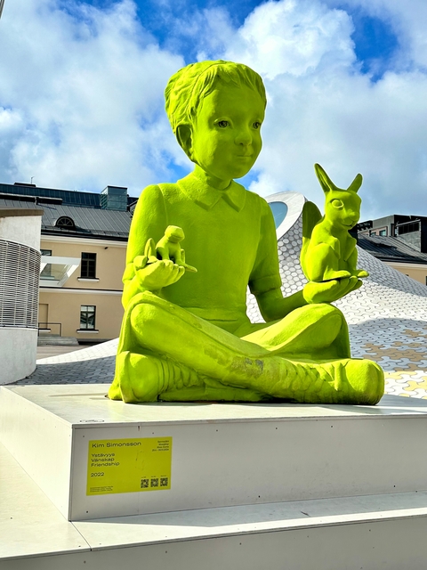       Bright green statue of a person with animals.
  