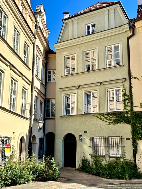 Exterior of pale building with ivy and open windows.