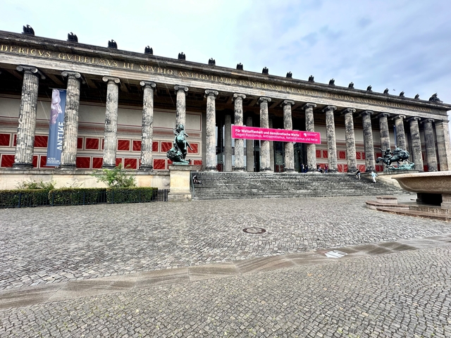 Large building with columns and red banners.