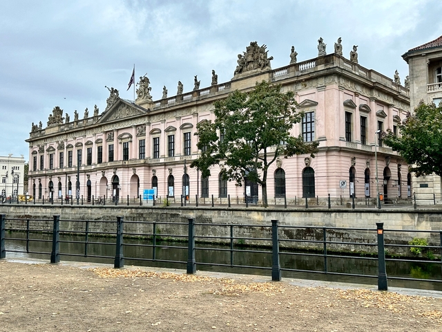       Classical building with statues and canal view.
  