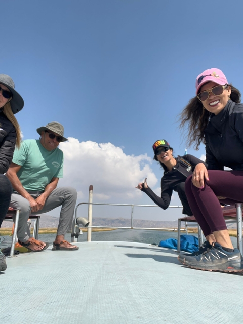 Group of people sitting outdoors, one wearing a hat with 'Peru' on it.