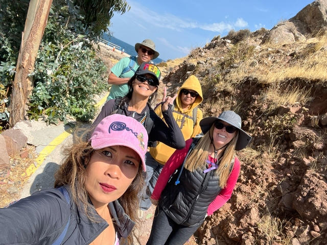 Five people posing on a hiking trail with mountains in the background.