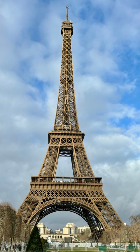 Close-up view of the Eiffel Tower in Paris under a cloudy sky.
