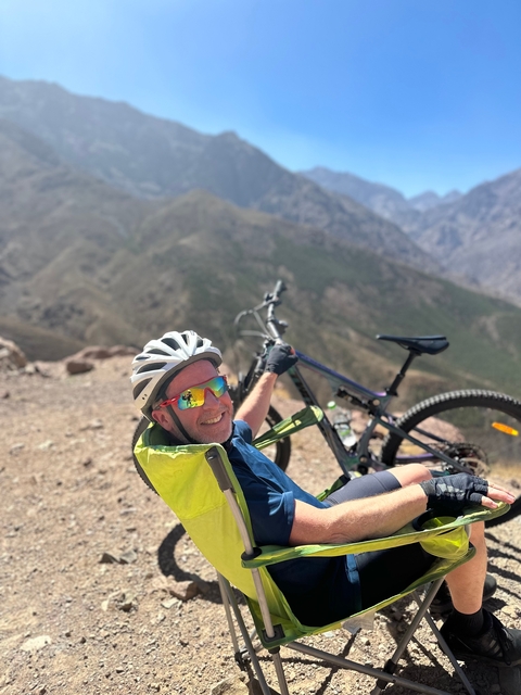 A cyclist relaxing with a mountain bike overlooking a valley.