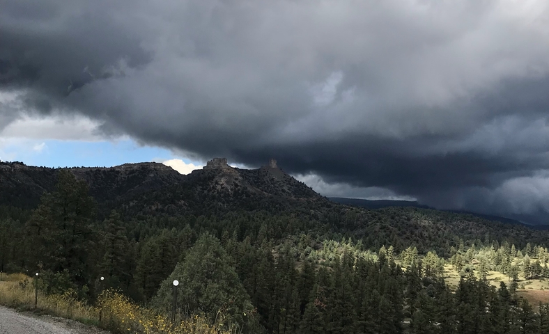 Scenic view of mountains and forests under storm clouds.