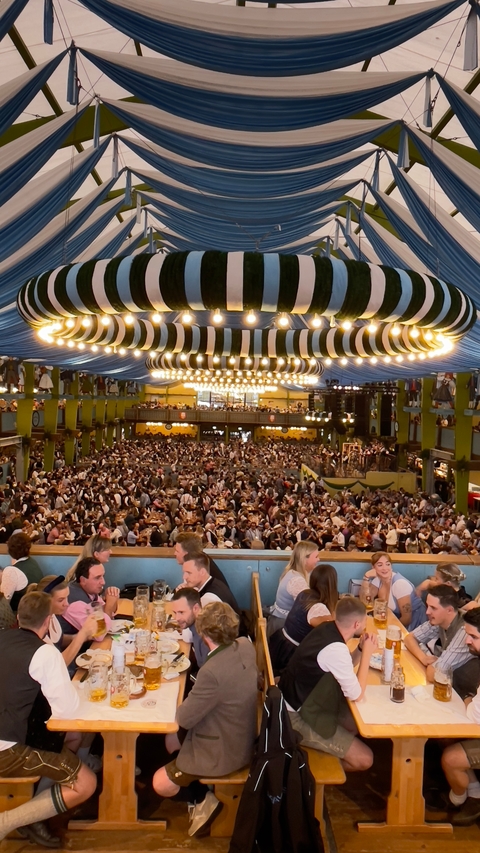 Crowded Oktoberfest tent with festive decorations.