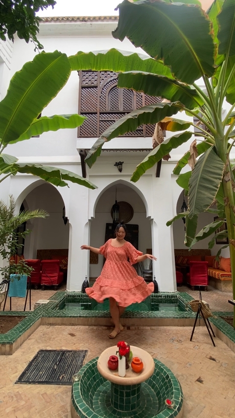       Woman dancing in a courtyard with Moroccan architecture.
  