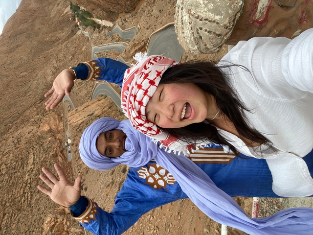 Two people posing with traditional clothing in a desert environment.