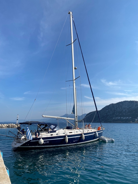 Sailboat at sea with mountainous coastline in the background.