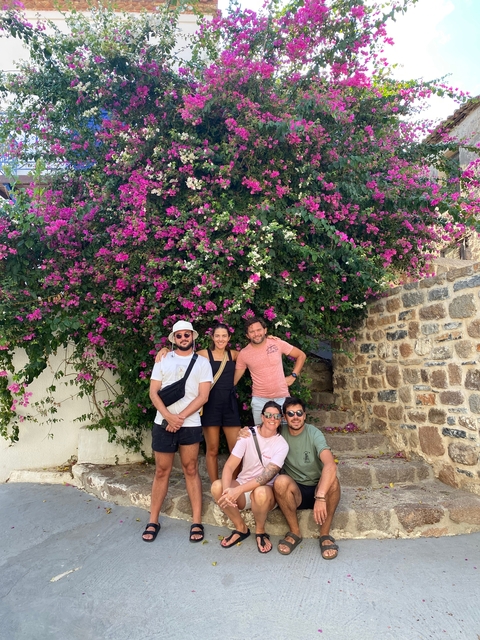 Group of people posing in front of vibrant pink flowers.