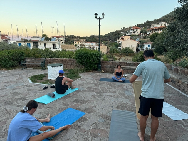 Group doing yoga on mats in a village setting.