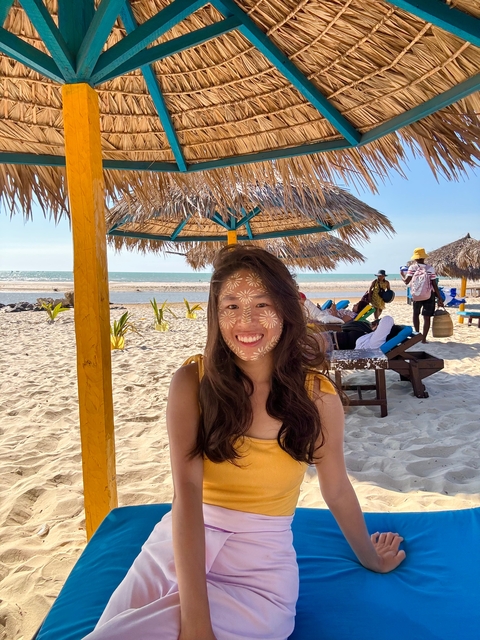       Person with traditional face painting on a beach.
  