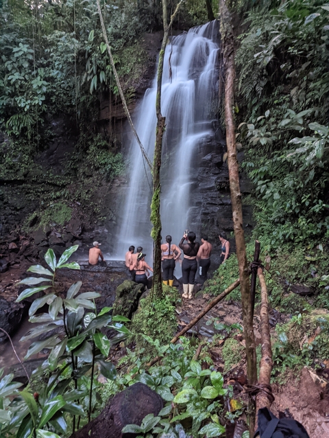 Group of people enjoying a waterfall experience.