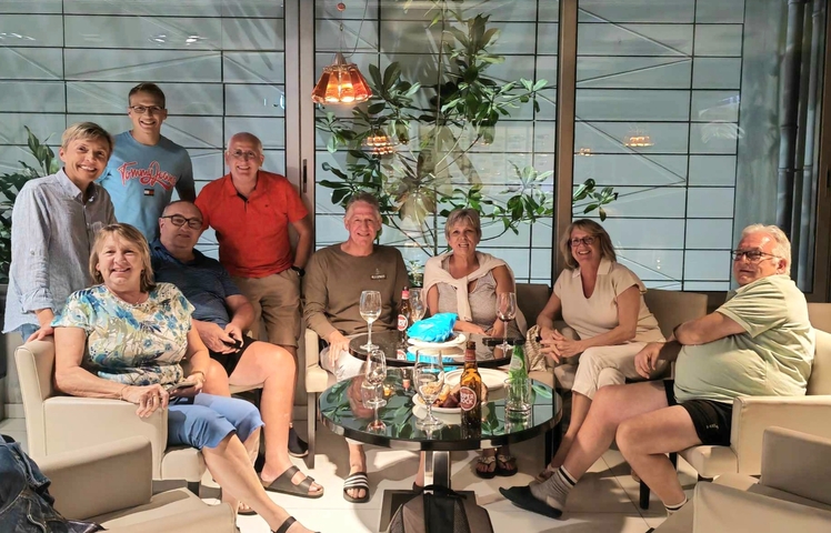 A group of people sitting indoors, posing for a group photo in a relaxed setting.