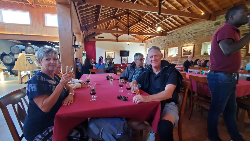 People enjoying drinks at a rustic indoor restaurant with wooden beams and a cozy atmosphere.