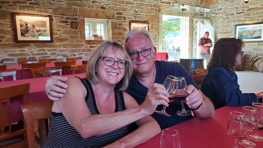 Couple holding wine glasses in a cozy restaurant with stone walls.