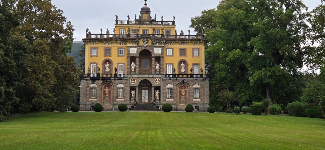       A heritage building with yellow facade and lush green lawn in front, likely a historical or cultural site.
  