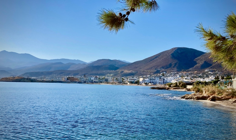 Coastal town with mountains in the background under a clear blue sky