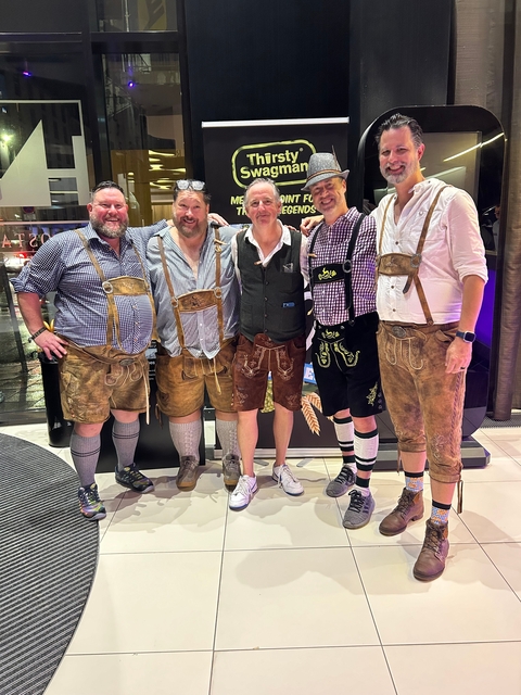 Men in traditional attire posing for a group photo indoors.