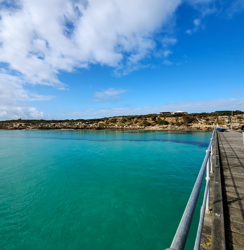 Coastal landscape with turquoise waters viewed from a pier.
