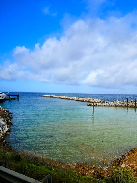 Calm small harbor protected by rocky barriers.