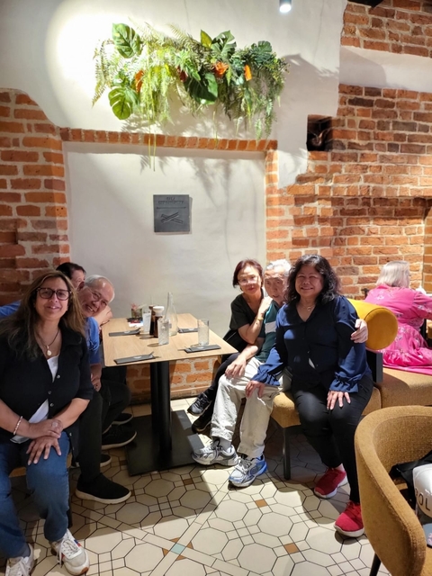 Group of people seated at a dining table in a brick-walled restaurant.
