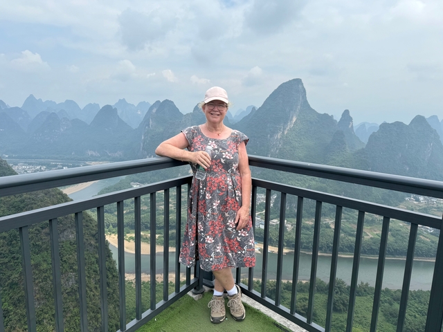 A person standing on a viewing platform with karst mountains in the background.