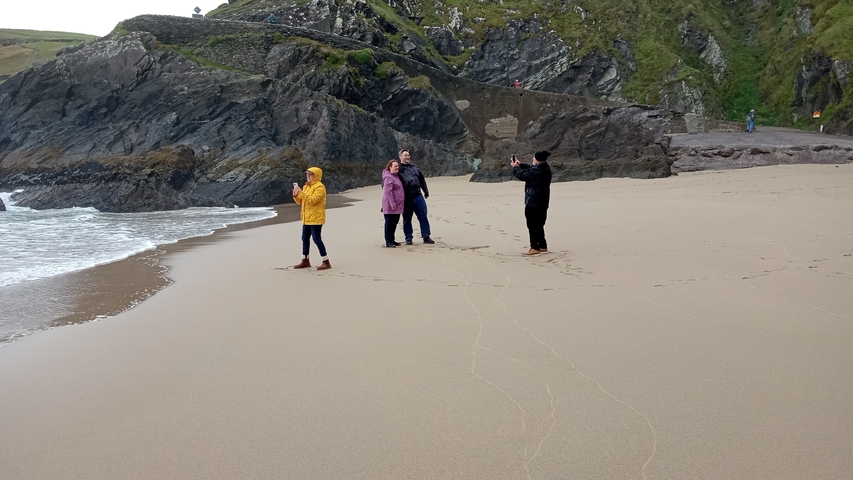       People enjoying a beach with rocky cliffs.
  