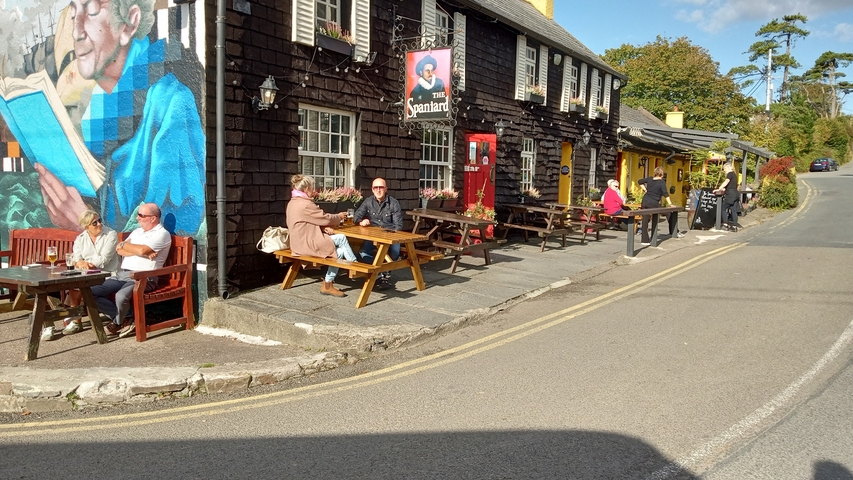 People seated outside a colorful pub.